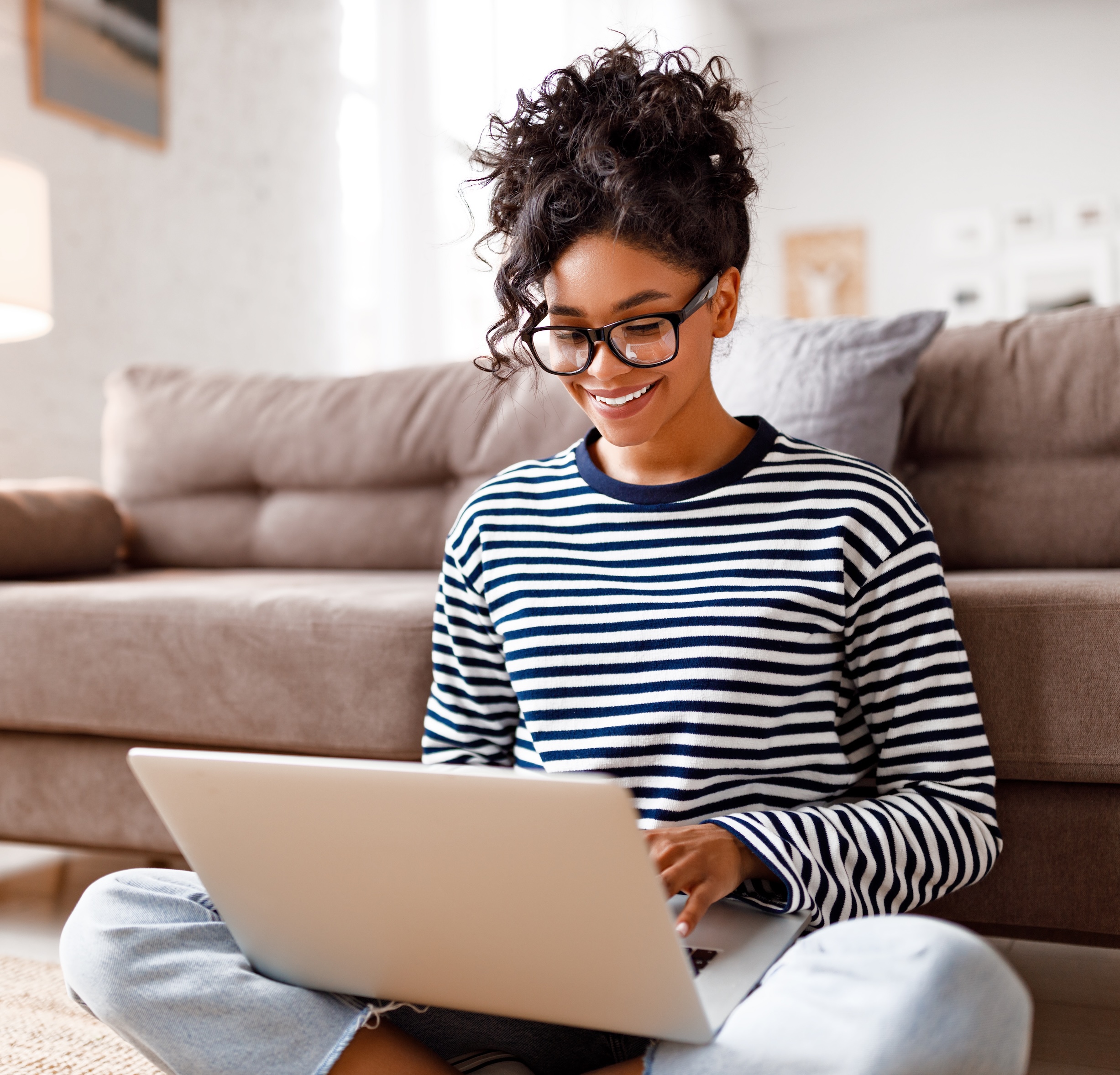 Joyful relaxed ethnic woman using laptop with interest at home